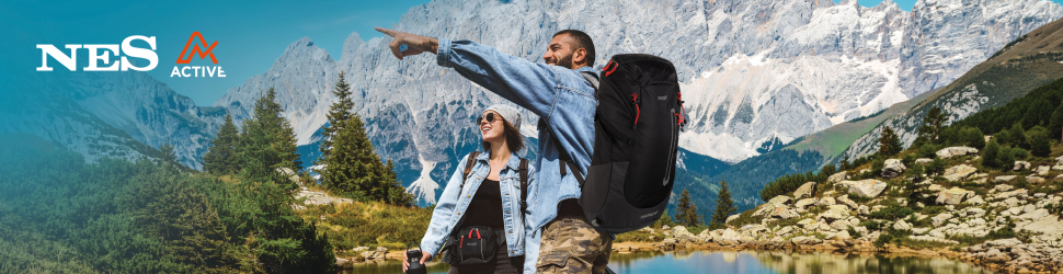 Dvoje planinara s ruksacima stoje uz planinsko jezero i gledaju prema vrhovima planina, dok muškarac pokazuje u daljinu; u kutu je logo NES Active.