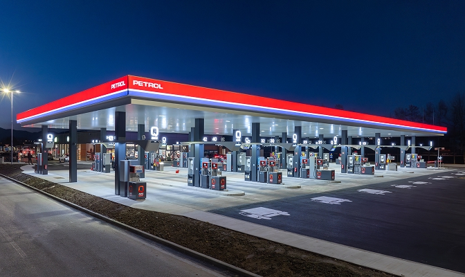 Noću osvijetljena benzinska postaja Petrol s crvenim nadstrešnicom i više redova uređaja za točenje goriva.