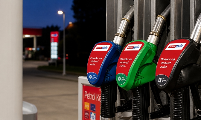 Tri ručke za točenje goriva u plavoj, zelenoj i crnoj boji na Petrolovu prodajnom mjestu, s istaknutim reklamnim porukama.